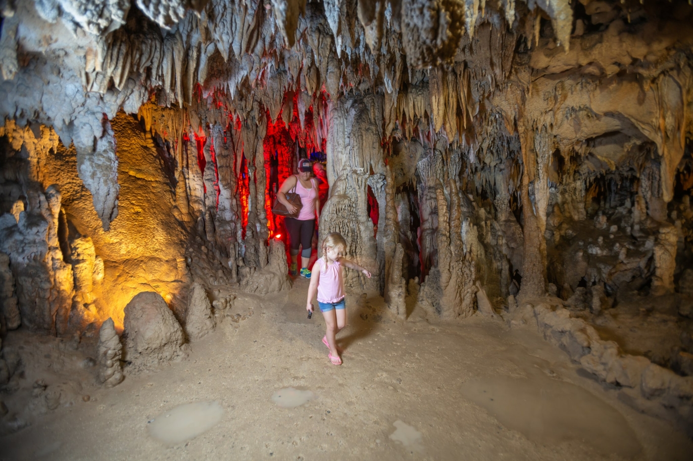 Image of a woman and a girl walking through the main cave at Falling Waters State Park.