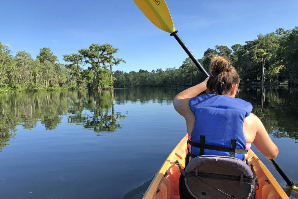 Image of a woman paddling on the water.