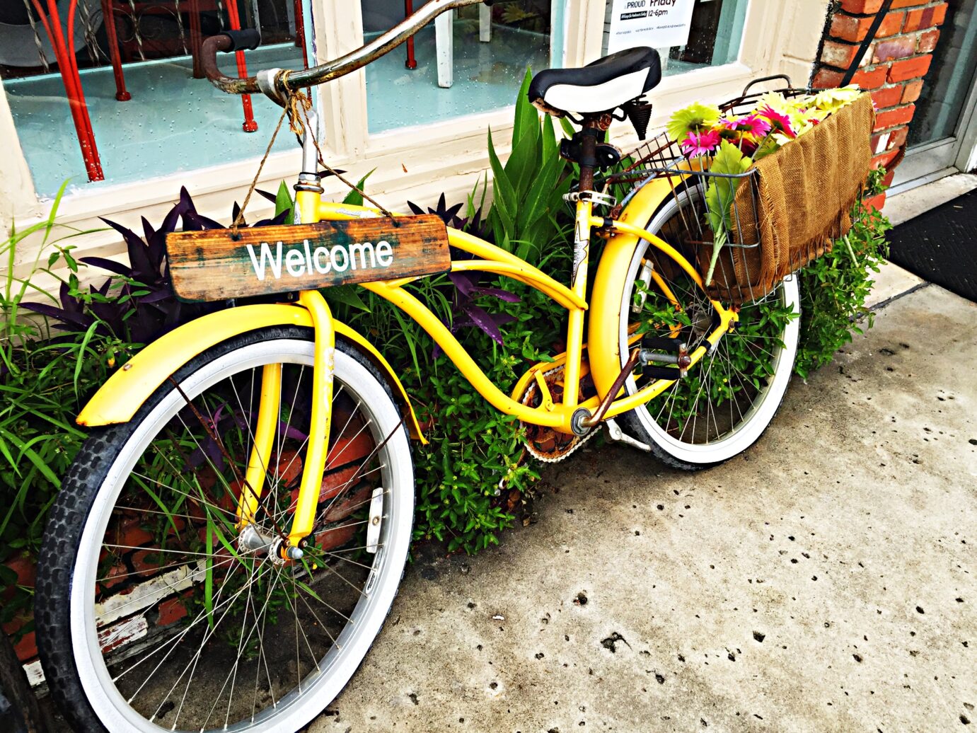 Image of welcome sign on a yellow bike with flowers.